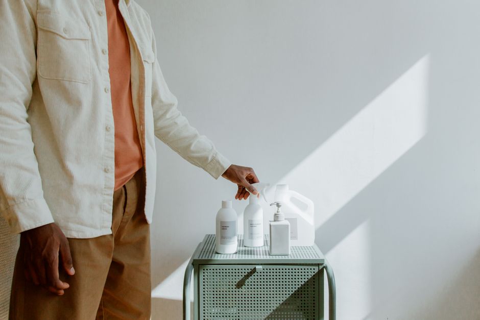 A person organizing cleaning products on a cart in a brightly lit indoor space.